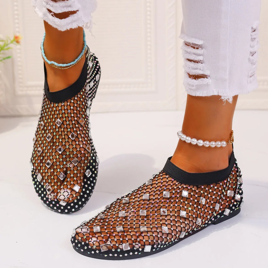 Women's flat sandals with colourful rhinestones on a mesh upper and rubber sole.