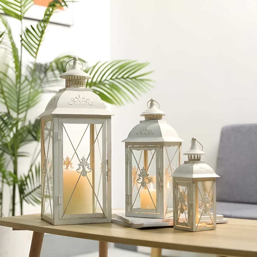 Black and white wrought iron floor-standing storm lantern with clear tempered glass panels on a garden patio.