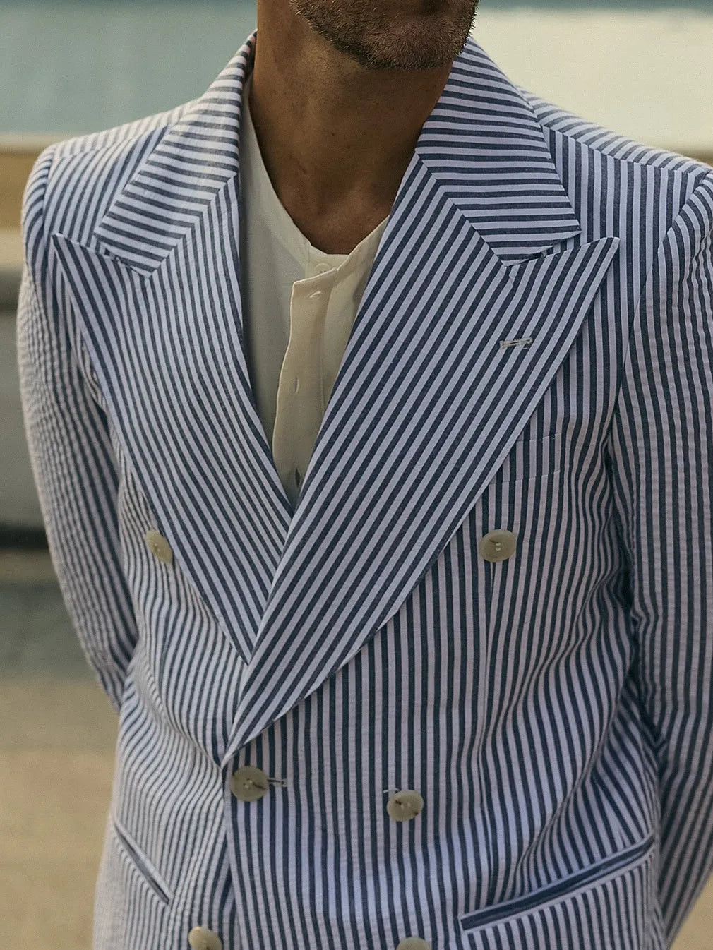Men's blue and white striped polyester suit set with regular fit blazer and trousers on a hanger.
