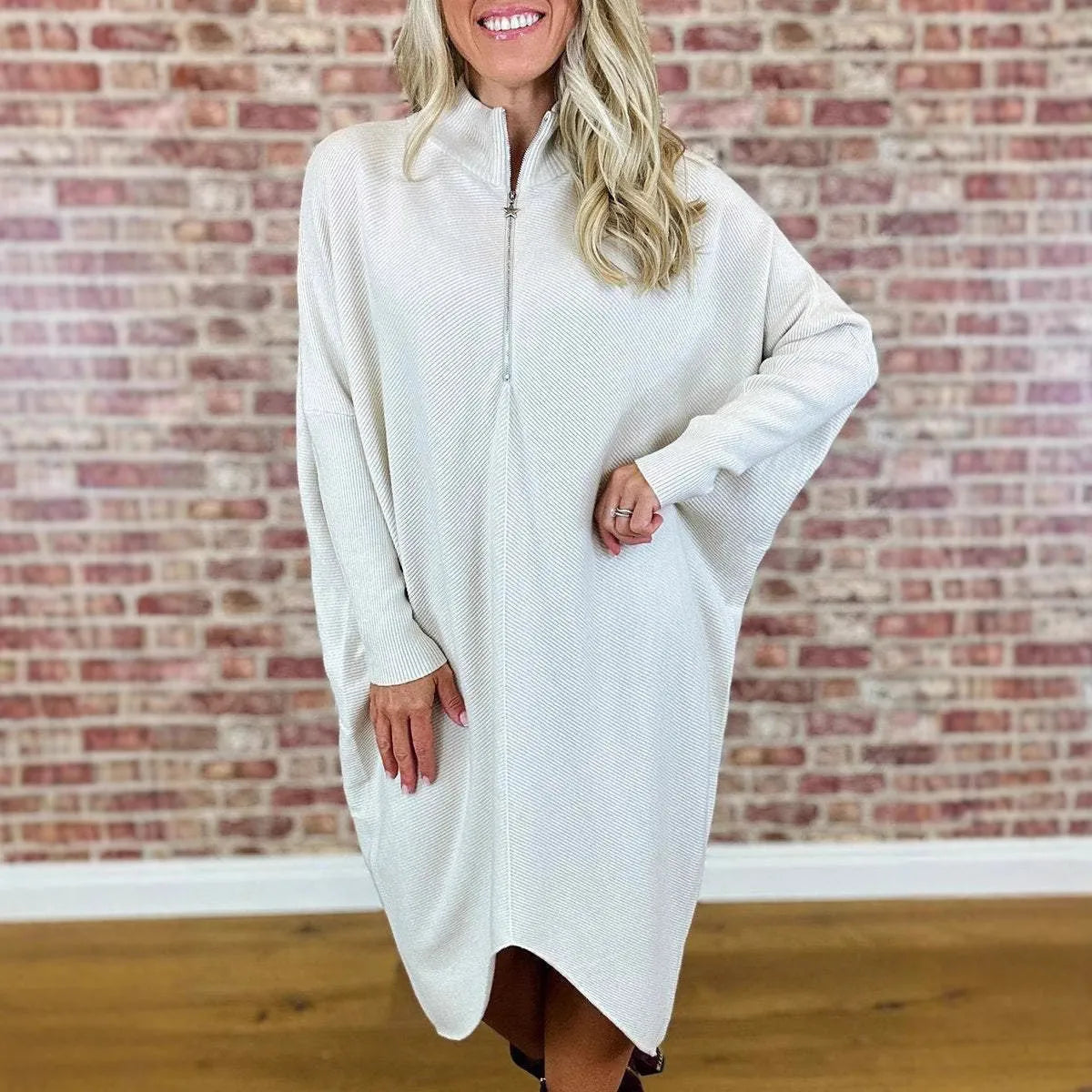Dark green loose knitted women's dress with full front zipper and raglan sleeves on a hanger.
