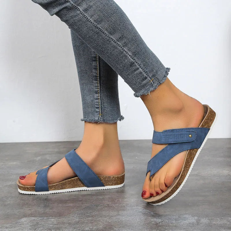 Flat toe ring flip-flops in blue with a thick foam sole on a wooden floor.