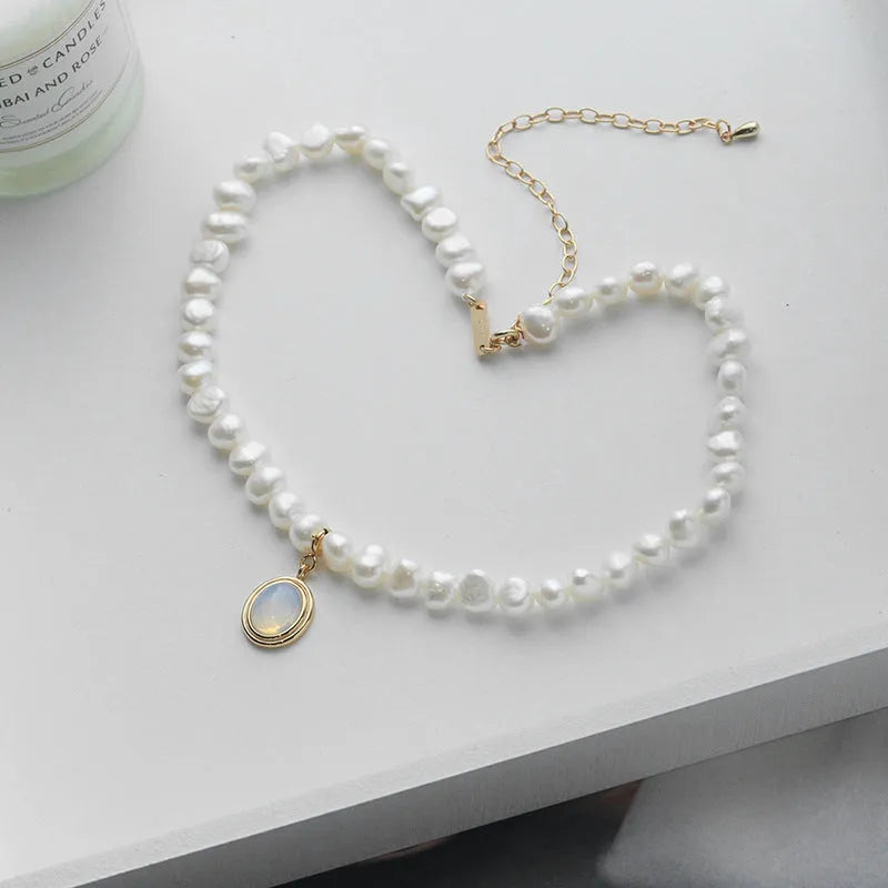 Geometric sterling silver necklace with irregular pearl pendant on a silver chain.