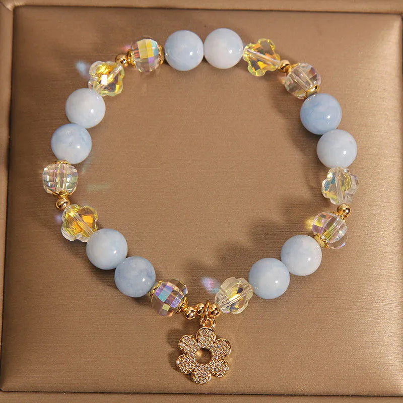 Women's aquamarine crystal bracelet with a four-leaf clover charm and pearl decorative elements.