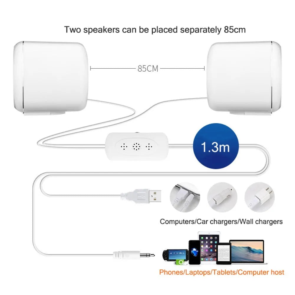 Pair of mini desktop speakers with 3.5mm audio plug on desk beside laptop
