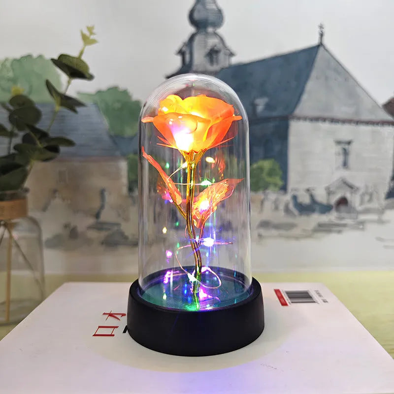 Small glass night lamp with plastic flowers on a black base.