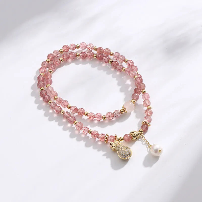 Close-up of a women's geometric bracelet made from pink strawberry quartz crystals.