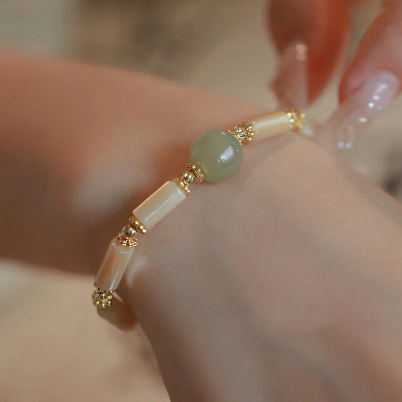 Simple geometric white Hetian jade bead bracelet for women on a wrist.