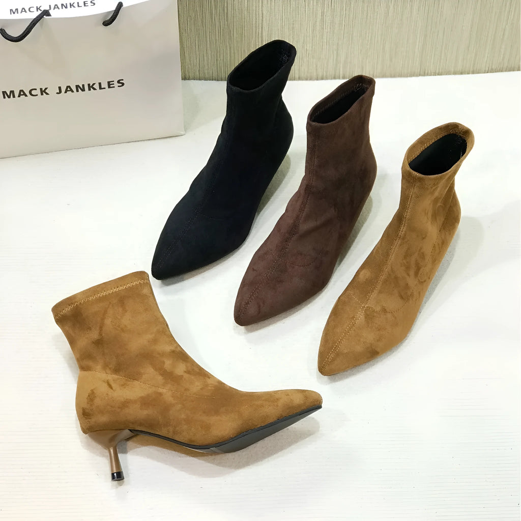 Black pointed toe women's ankle boots with stiletto heel on a plain background