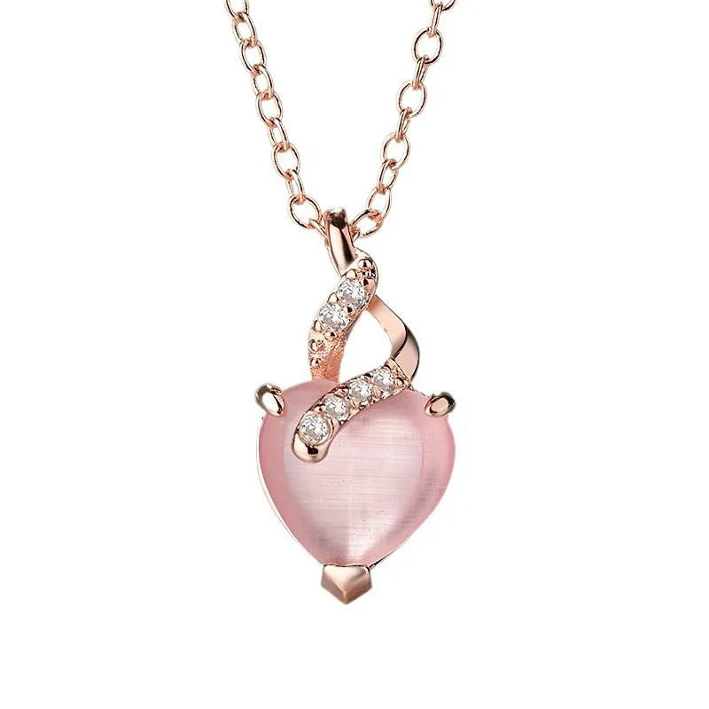 Women's rose gold necklace with a heart-shaped pink crystal pendant on a cross chain.