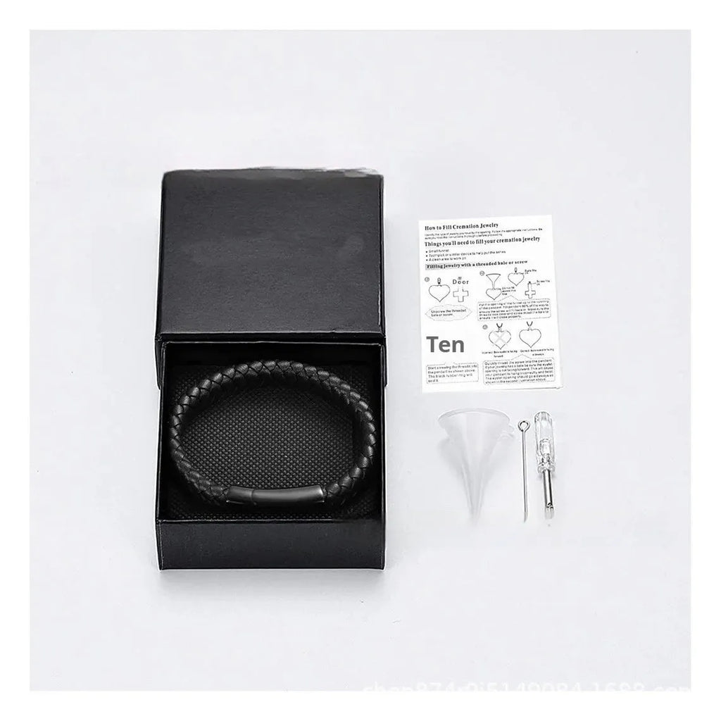 Black leather bracelet with a small stainless steel casket charm, shown in a gift box.