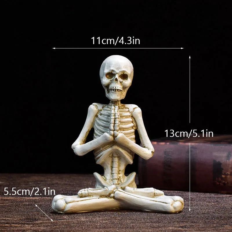 Detailed resin Halloween ornament of a yoga-posing skeleton skull on a desktop.