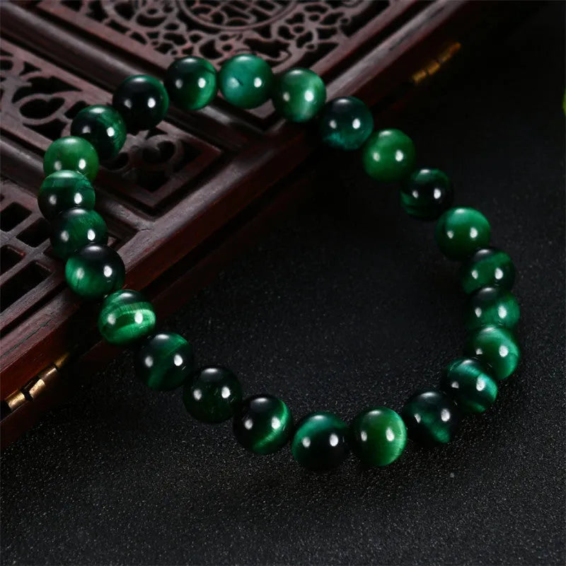 Green tiger eye stone bracelet with polished geometry beads on a wrist, showing the stone's natural banding.