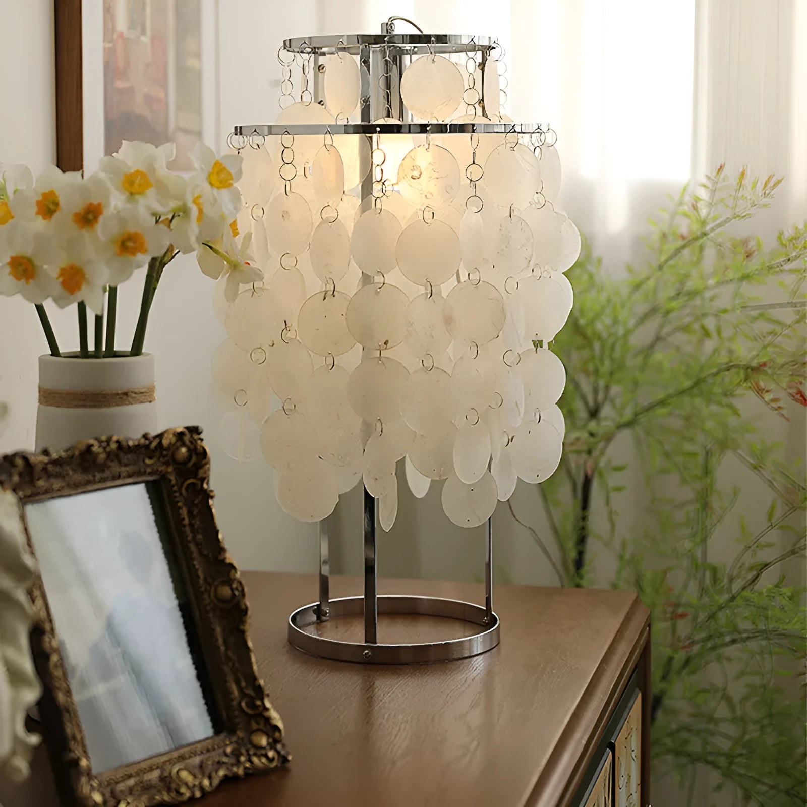 Modern shell-shaped metal bedside table lamp in chrome finish on a wooden table.