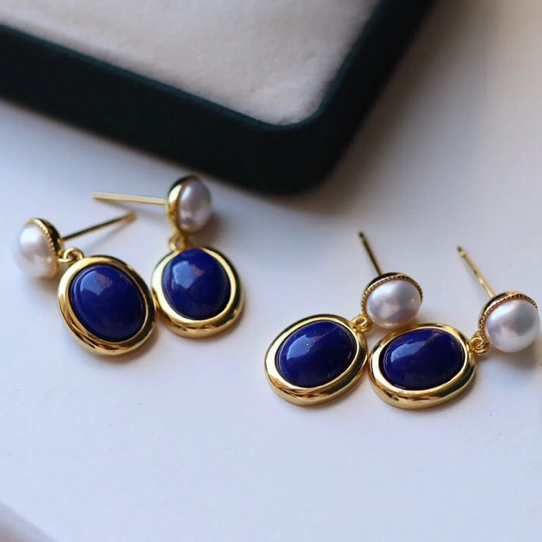 A pair of simple sterling silver earrings featuring blue lapis lazuli pearls and auspicious pattern detailing.