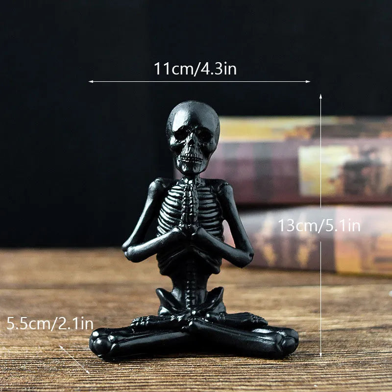 Detailed resin Halloween ornament of a yoga-posing skeleton skull on a desktop.