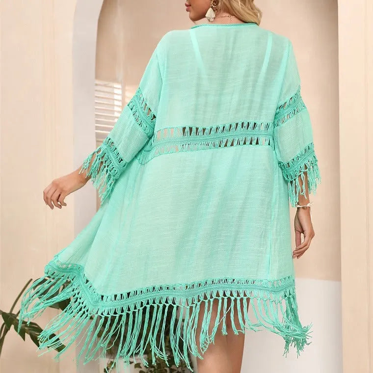 Yellow hand-crocheted women's cardigan with tassel stitching, laid flat as a beach cover-up.