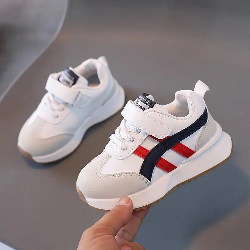 Children's white synthetic leather sneakers with Velcro strap and rubber sole.