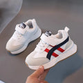 Children's white synthetic leather sneakers with Velcro strap and rubber sole.