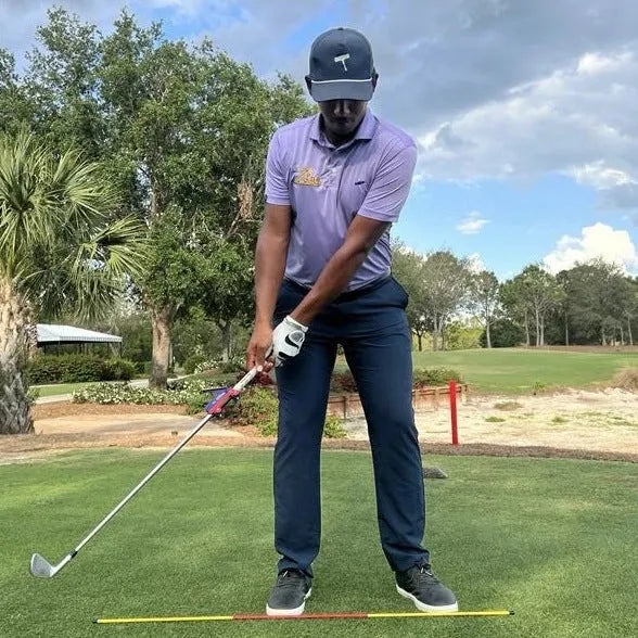 Plastic golf swing plane simulator training aid on a green surface.