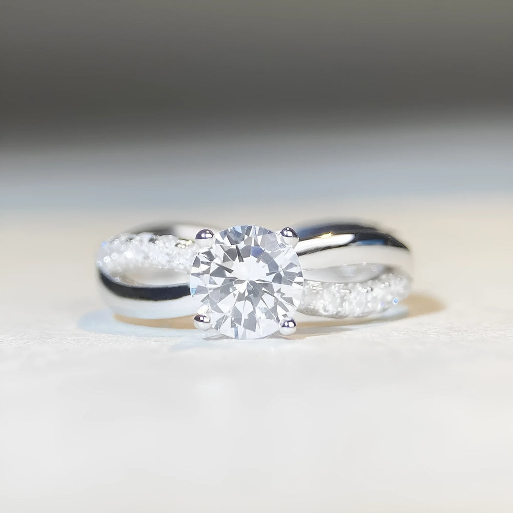 Close-up of a twisted sterling silver band moissanite ring with a four-claw setting and geometric lines.