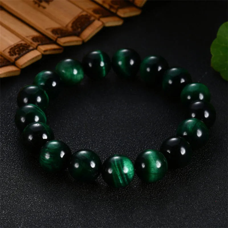 Green tiger eye stone bracelet with polished geometry beads on a wrist, showing the stone's natural banding.