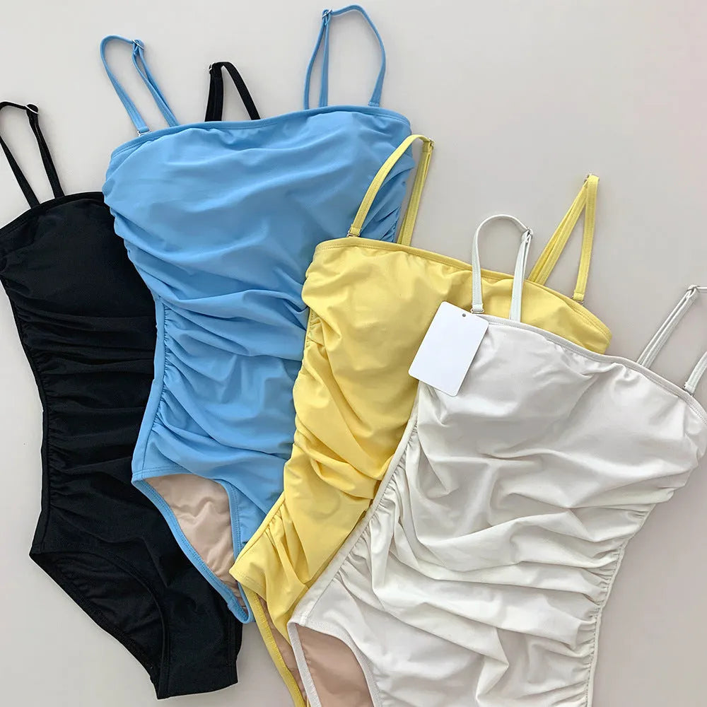 Sling style one-piece swimsuit with belted waist and pleated design in nylon fabric