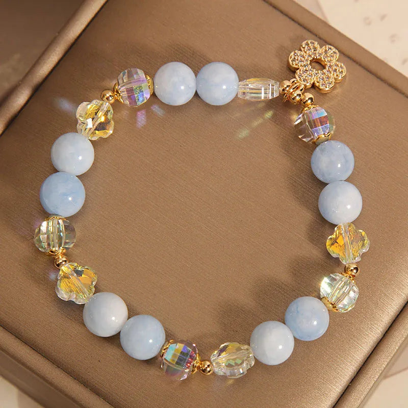 Women's aquamarine crystal bracelet with a four-leaf clover charm and pearl decorative elements.