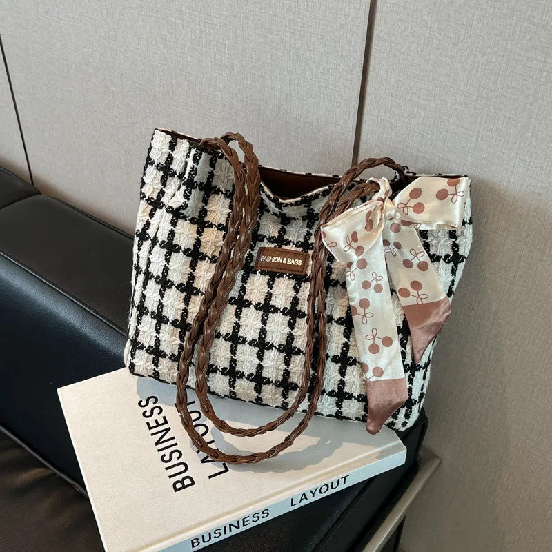 Black woven wool shoulder bag showing horizontal square shape and external pocket.