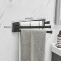 Black folding towel bar mounted on a bathroom wall with adhesive, shown in extended and folded positions.
