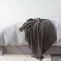 Small light grey polyester blanket folded on a sofa