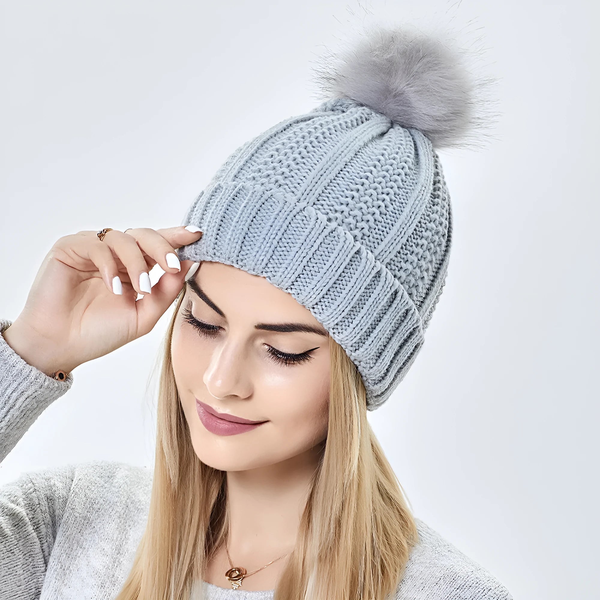 Women's knitted beanie hat with faux fur pom pom, shown with satin lining exposed, available in multiple colours.