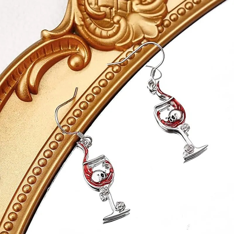 Pair of geometric drop earrings with combined skull and wine glass design in metallic finish.