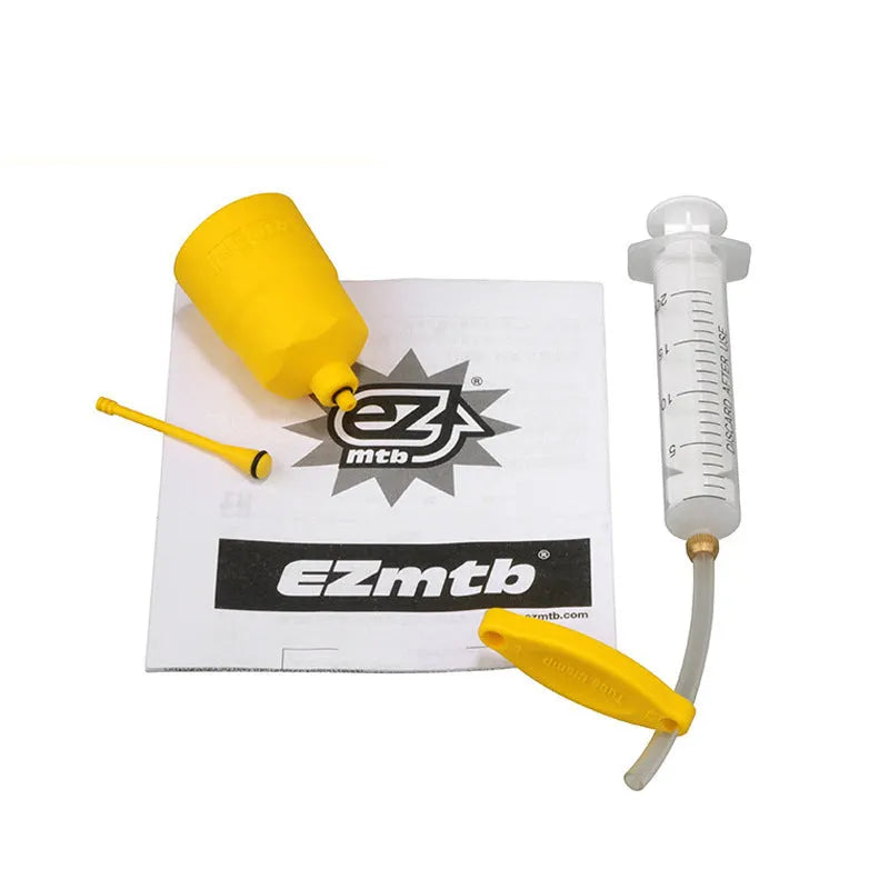 EZmtb bicycle hydraulic brake bleed kit showing syringes, metal fittings, adapters, and tools on a workbench.