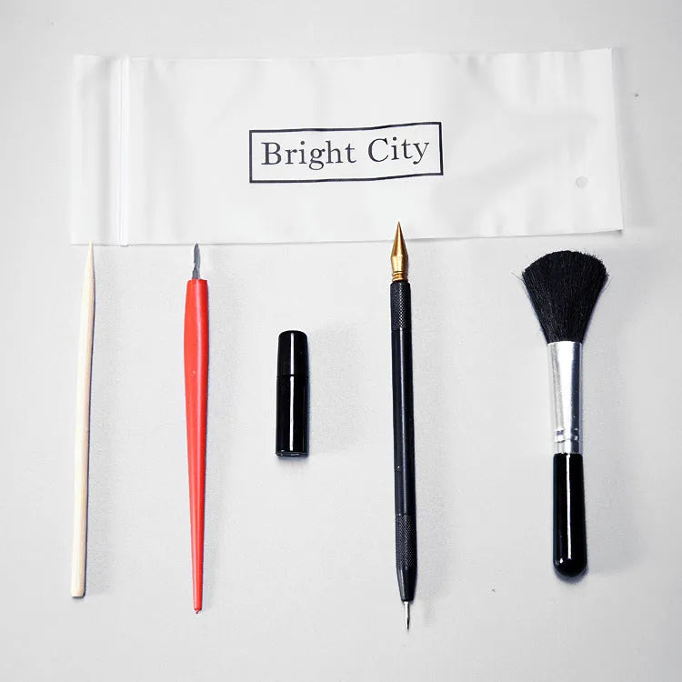 Scratch art pen tool kit with scraper, repair solution, brush, and bamboo stick on a craft table