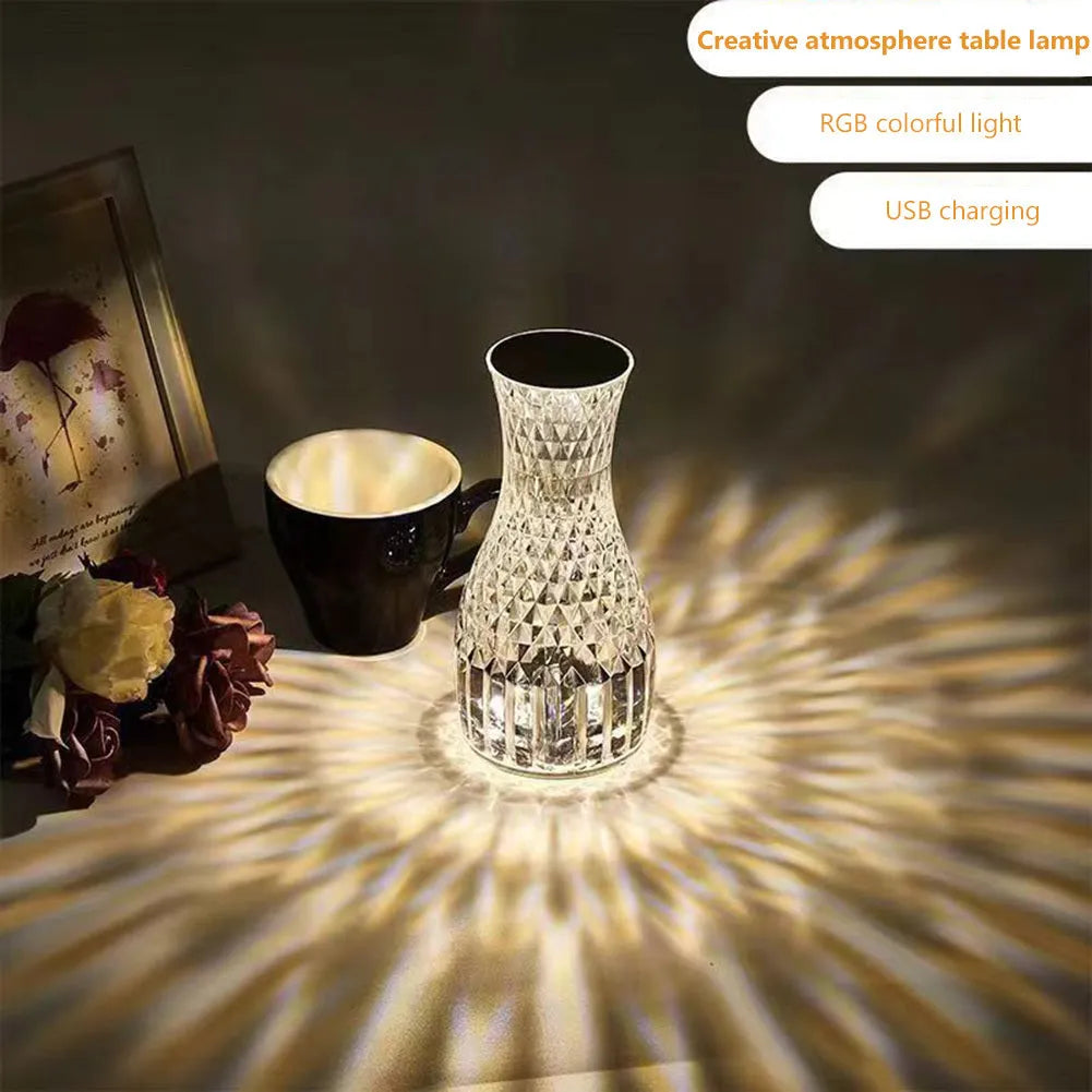Transparent vase-shaped crystal LED table lamp with multi-colour lights on a wooden table.