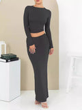 Women's black polyester two-piece suit with exposed navel top and long skirt.