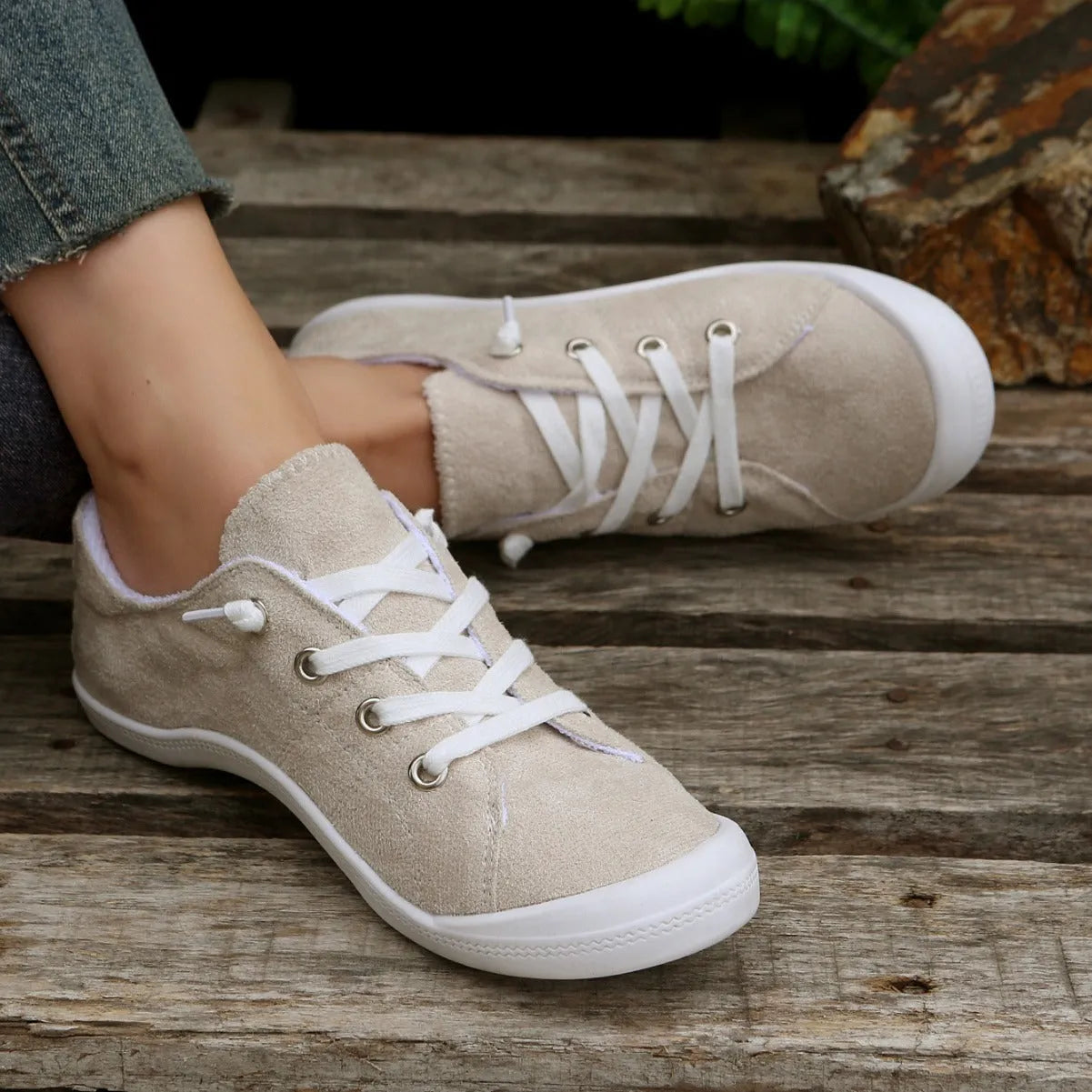 Women's creamy white beige fabric low-top casual sneakers with a rubber sole on a plain background.