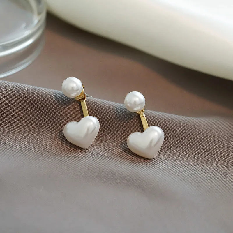 Close-up of a women's heart-shaped alloy stud earring with electroplated finish and central gemstone inlay.