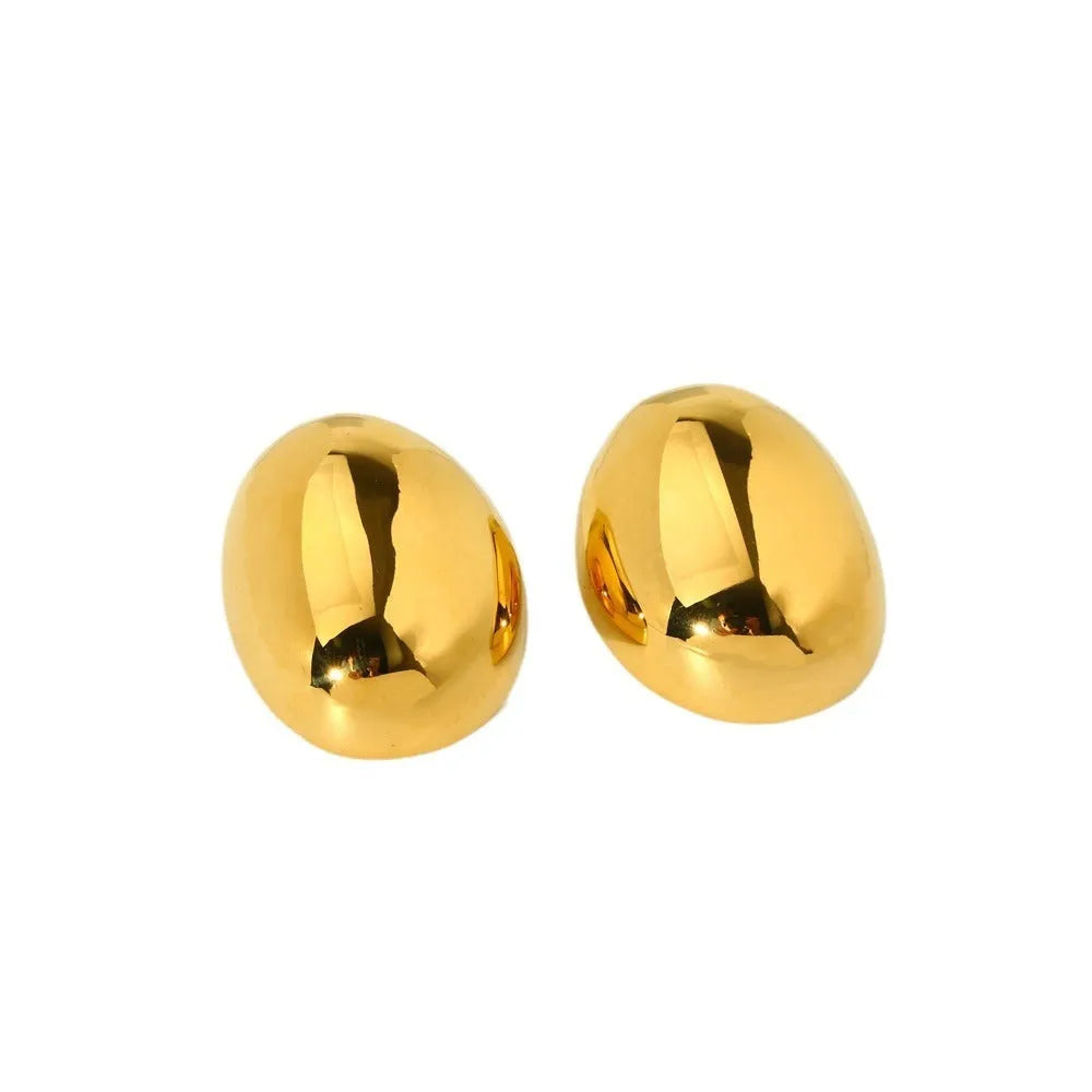 A pair of geometric gold-coloured ear studs with a glazed finish and exaggerated line details on a white background.