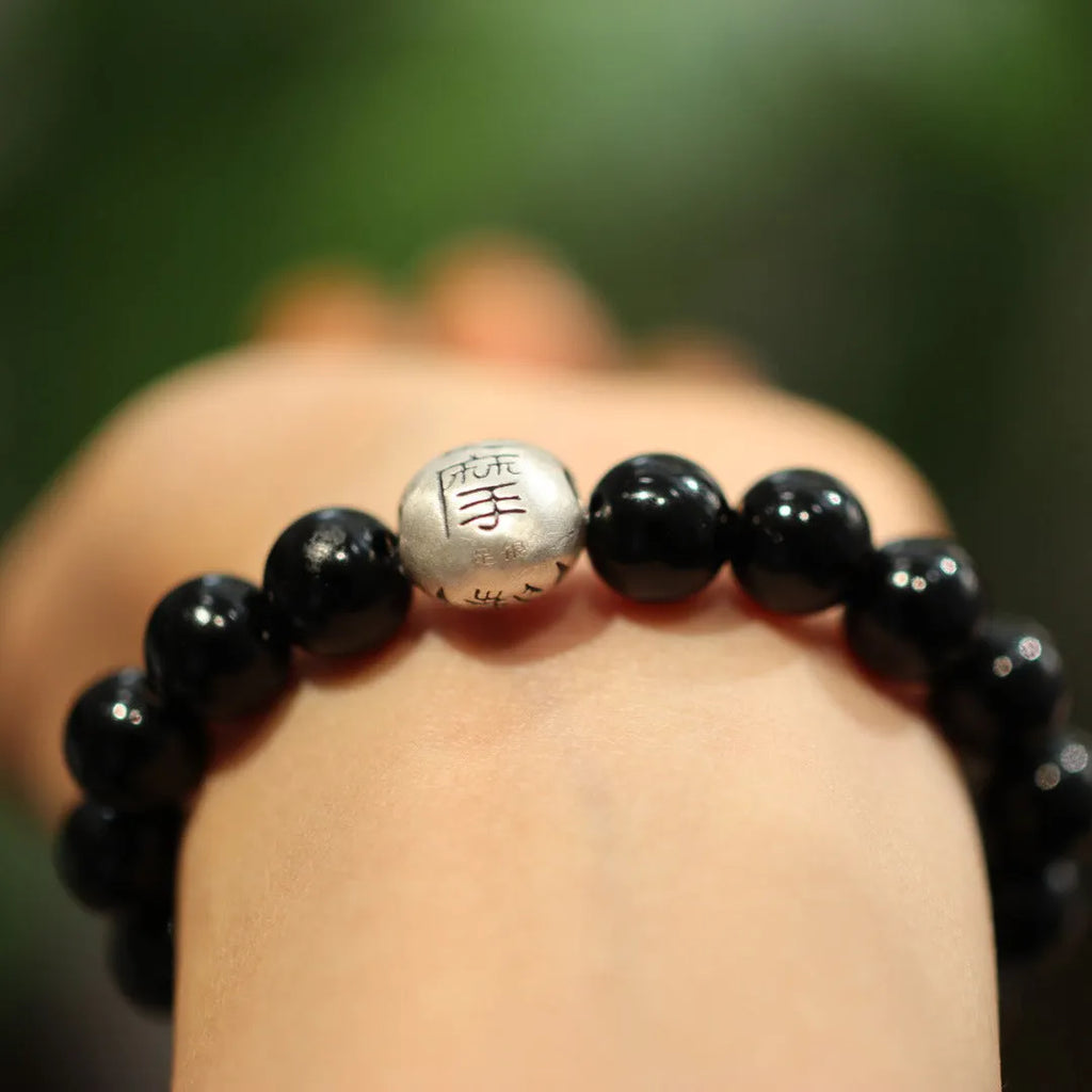 Close-up of a black agate and sterling silver bracelet showing 10mm beads and detailed clasp.
