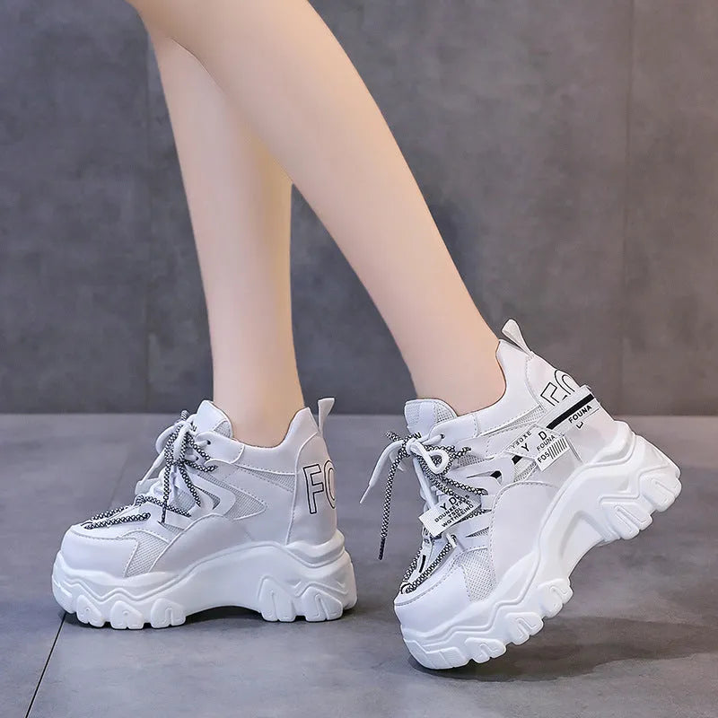 Women's white low-top platform trainers with mesh panels and a black cross-strap over the vamp.