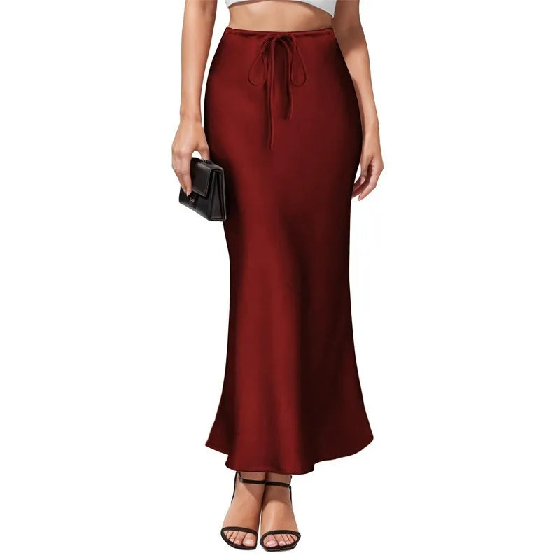Women's high-waisted asymmetric satin skirt in black on a hanger, showing irregular hem detail.