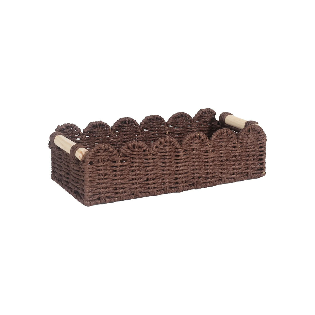Modern simple woven paper storage basket in neutral colour on a wooden desktop holding remote controls and pens.