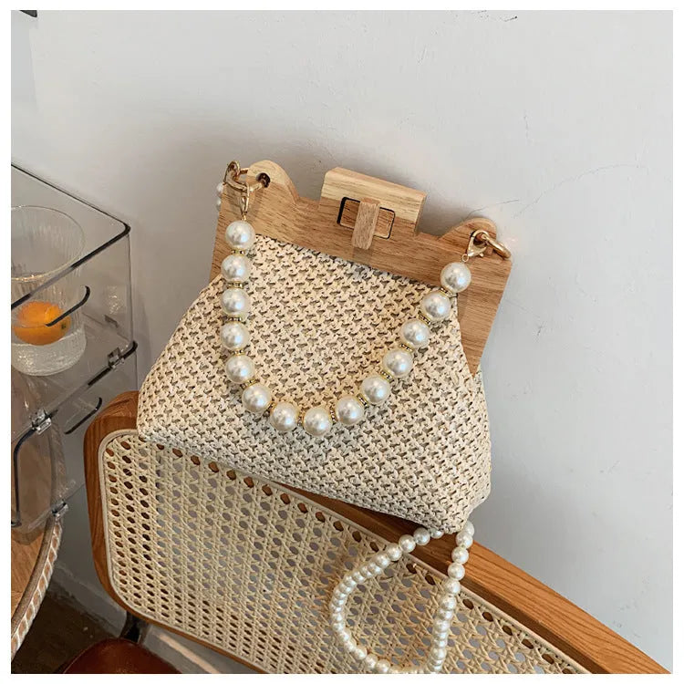 Women's straw shoulder bag with pearl chain detail and multiple zipper compartments in neutral colour