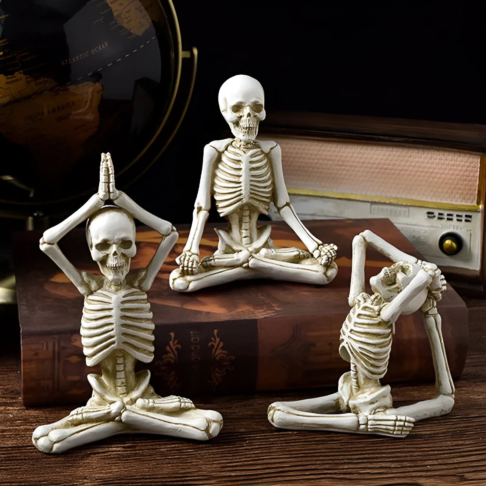 Detailed resin Halloween ornament of a yoga-posing skeleton skull on a desktop.