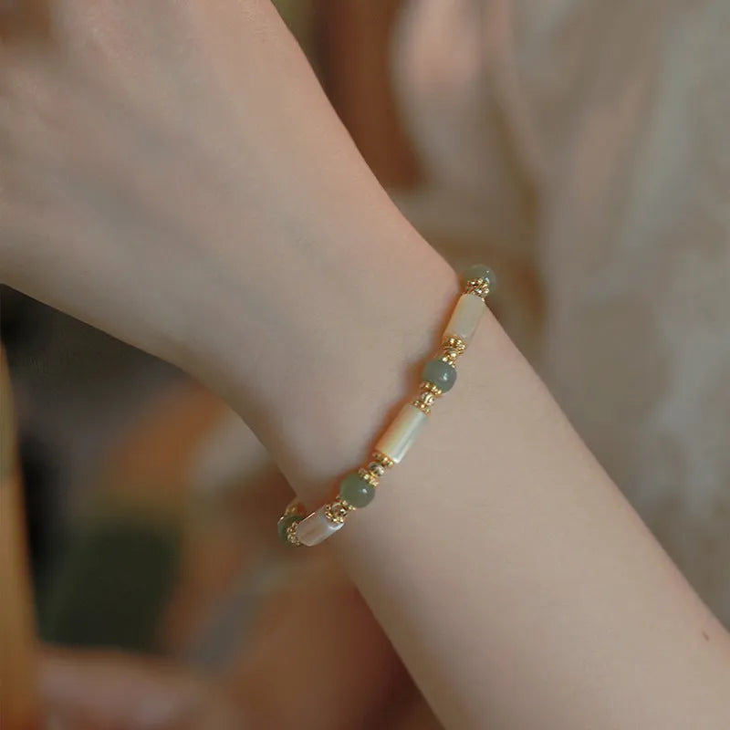 Simple geometric white Hetian jade bead bracelet for women on a wrist.