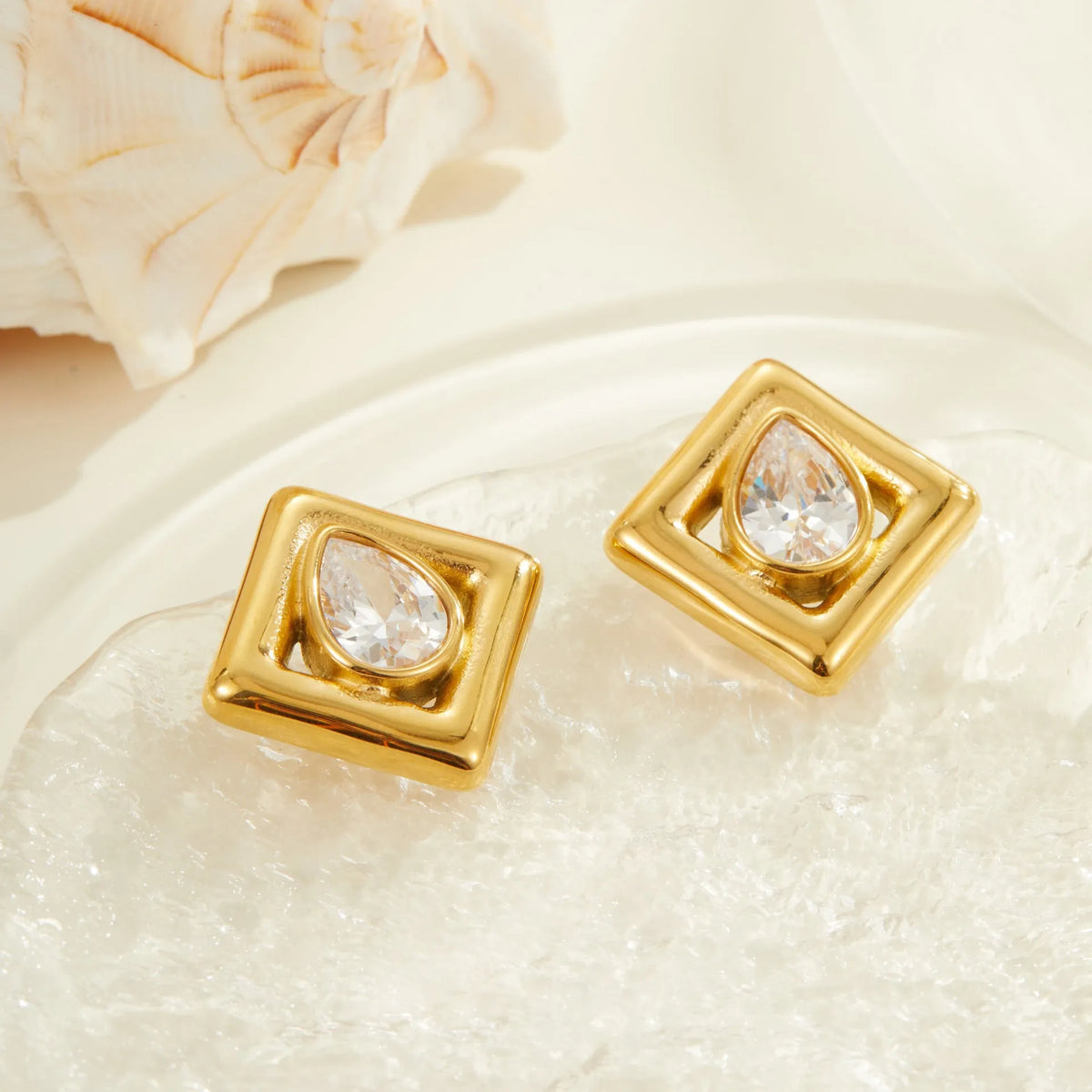 Gold coloured geometric stud earrings with an inlaid water drop zircon stone.