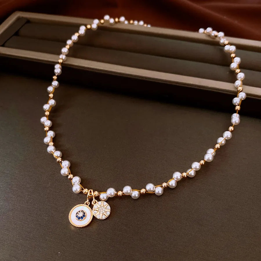 Gold electroplated women's necklace with round zircon and imitation pearl pendant on an adjustable clavicle chain.