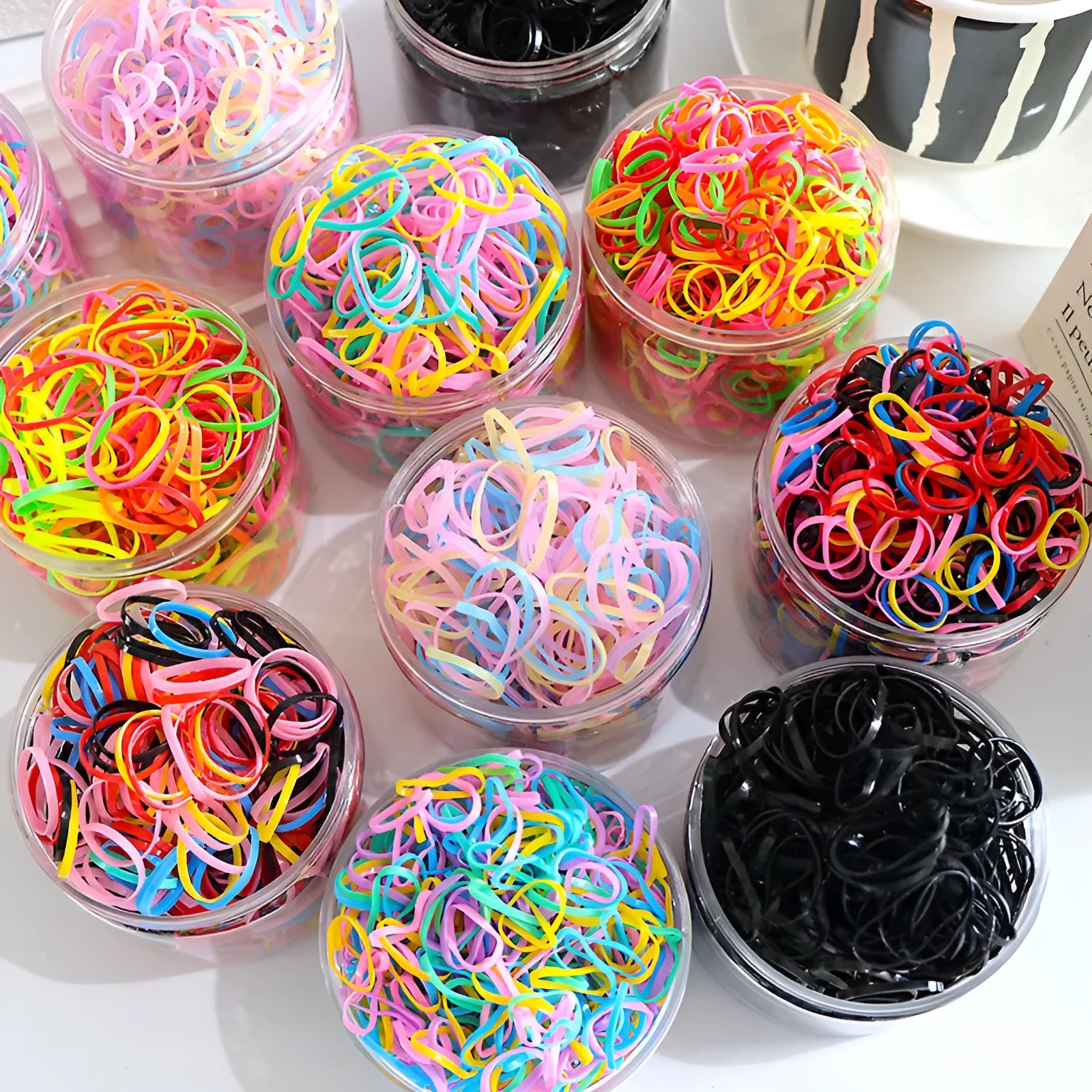 Multi-colour TPU baby hair bands in a reusable container, 300 or 600 piece pack.