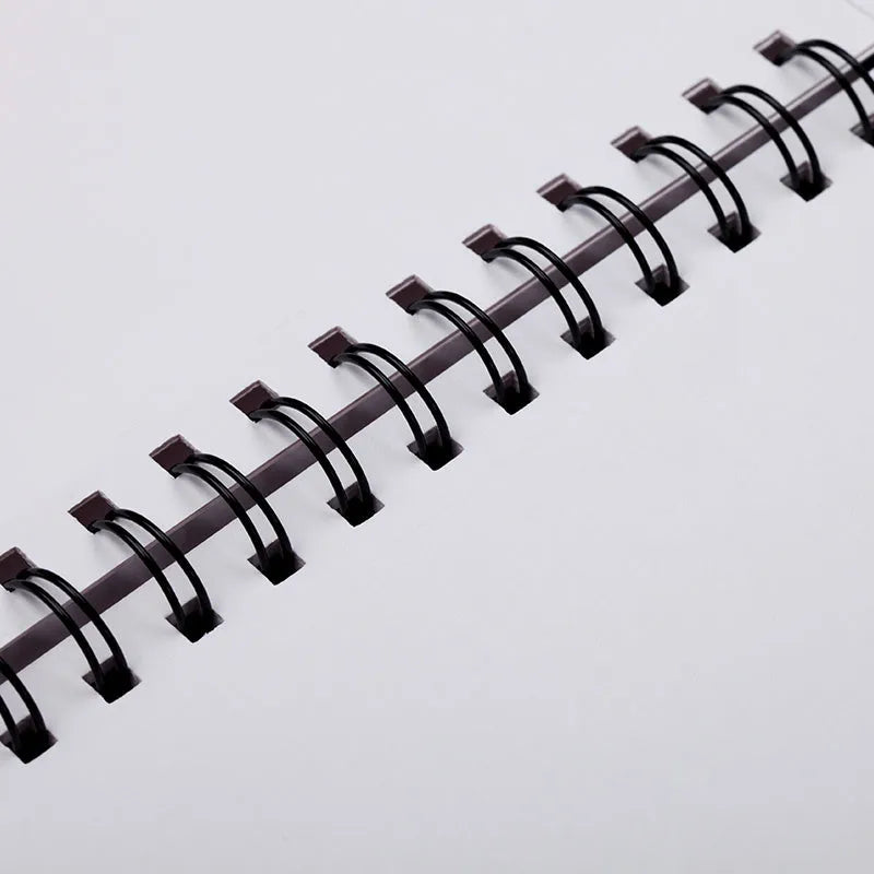 A4 sketchbook with coil binding lying flat open, showing blank heavyweight drawing paper.